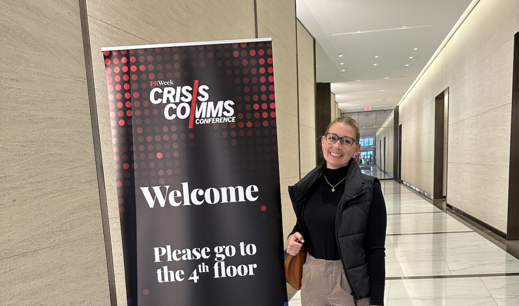 Hannah standing next to a sign at PR Week's Crisis Communications conference.